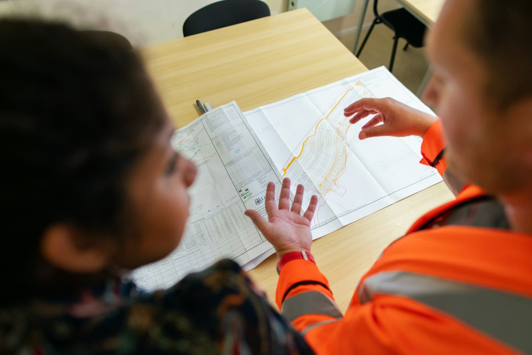 A civil engineer discussing a weir project on site with a colleague